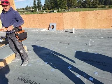 A man is standing on a roof with a bag on his waist.