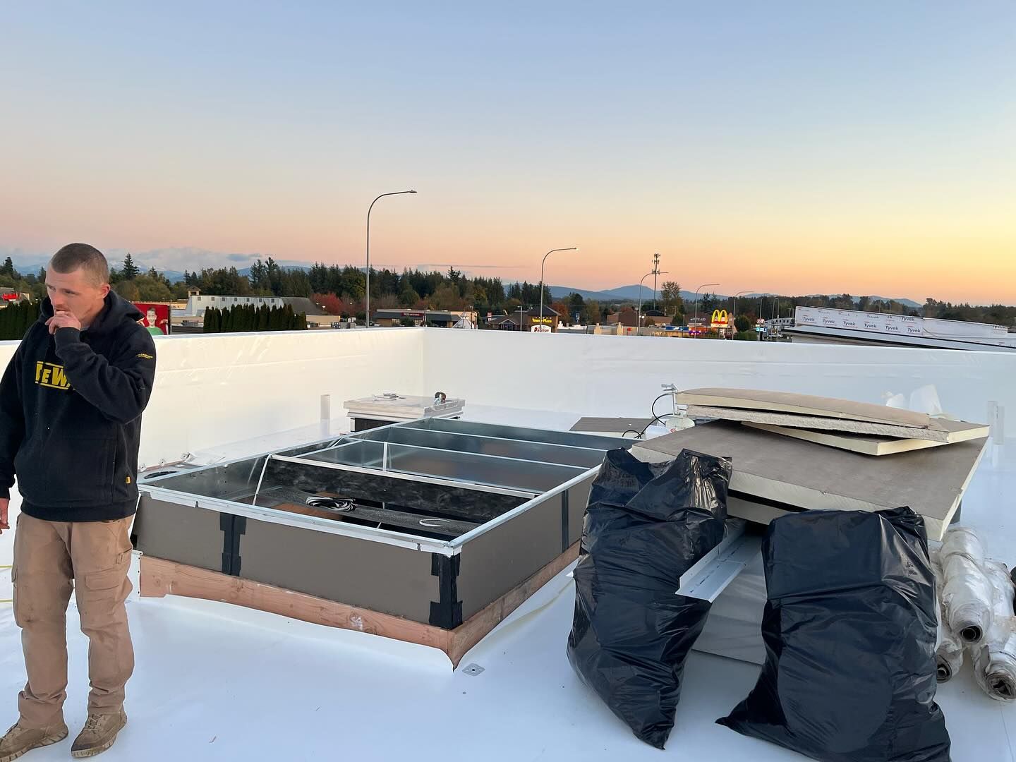 A man is standing on top of a commercial flat roof.
