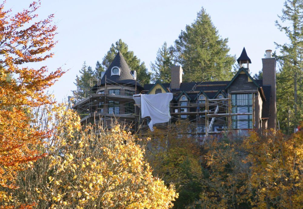 A large house is being built on top of a hill surrounded by trees