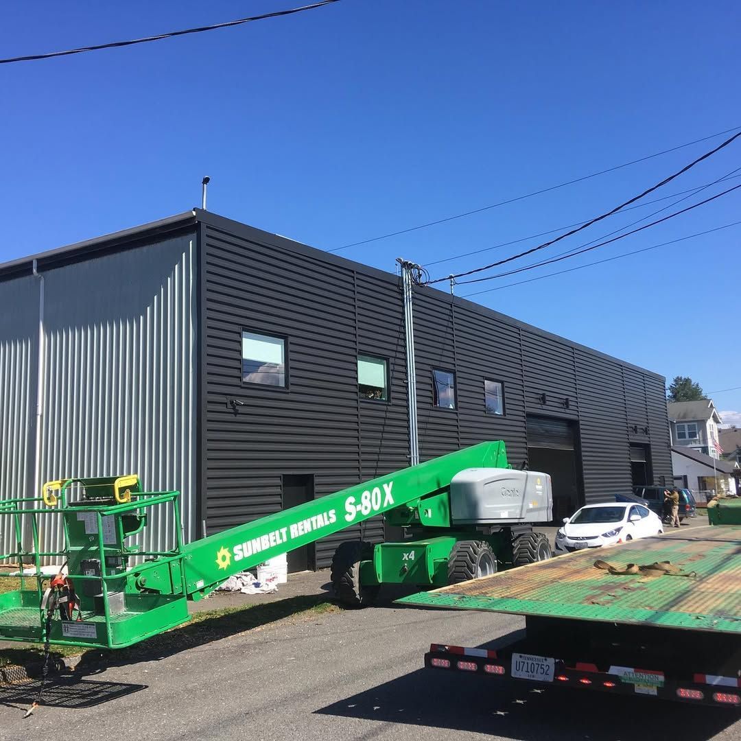 A green crane is parked in front of a building.