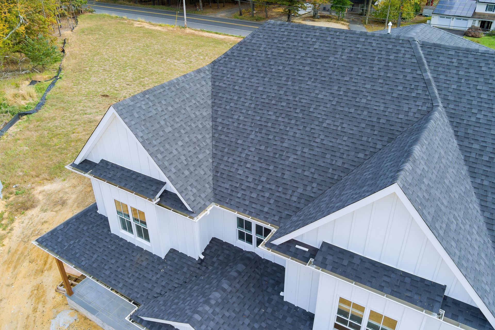 An aerial view of a white house with a black shingle roof.