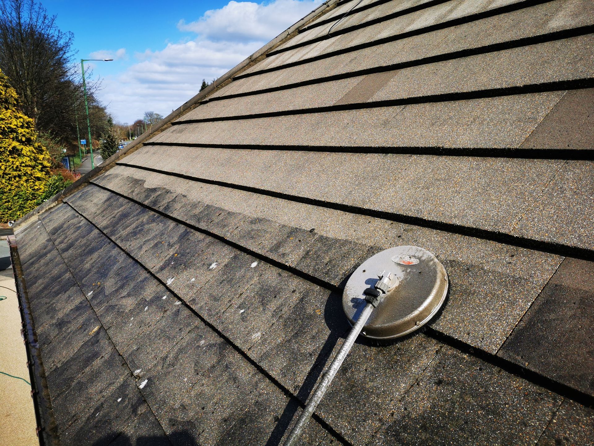 A person is cleaning the roof of a house with a brush.